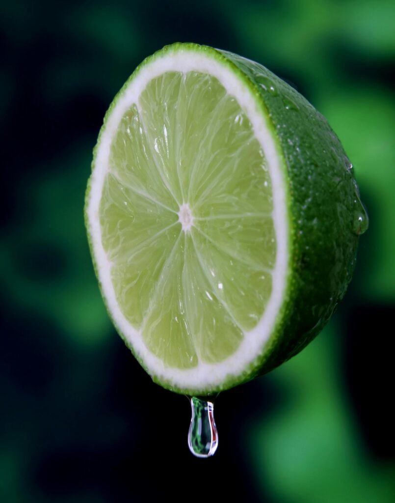 Macro shot of a juicy, fresh lime slice with a water droplet, highlighting its vibrant green color.