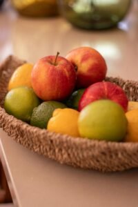 Colorful fruit basket with apples, lemons, and limes on a table.
